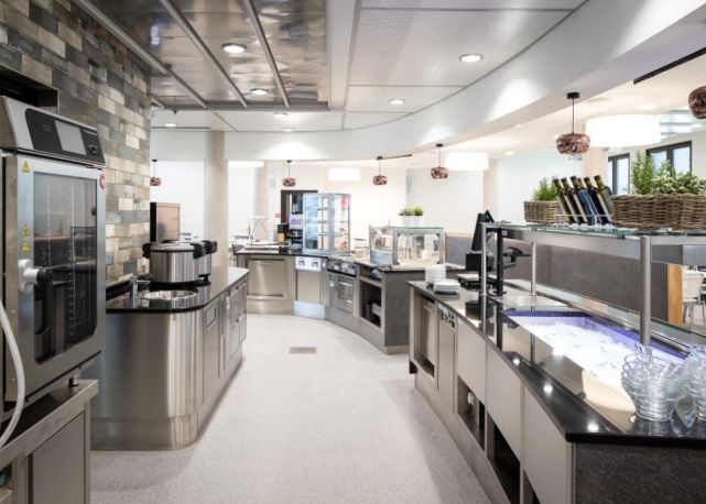 Eine moderne Küche mit Edelstahlgeräten und Arbeitsflächen aus Edelstahl, auf beschichtetem Boden, die Eleganz und Funktionalität vereint.